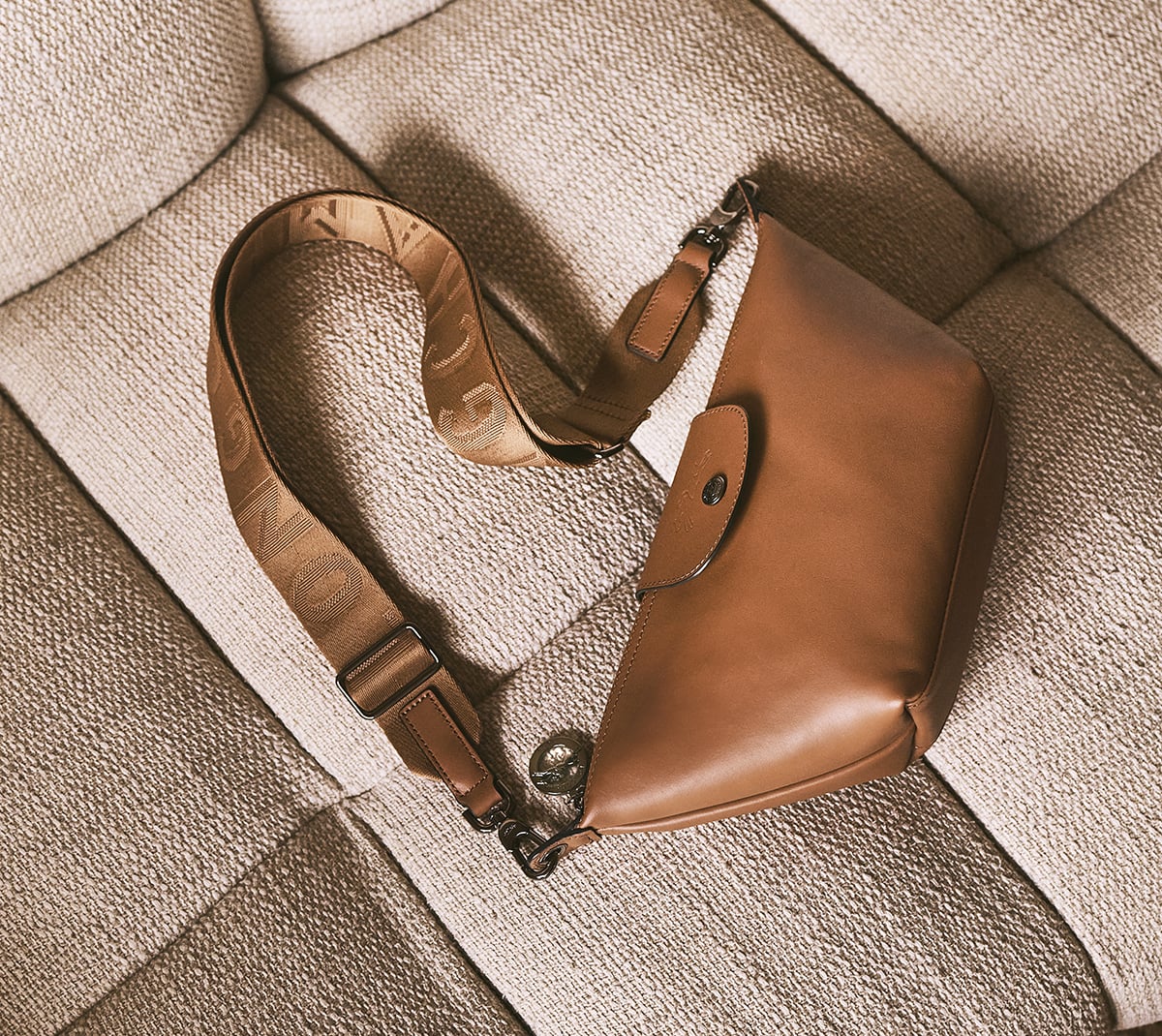 Longchamp leather shoulder bag resting on a woven cushion